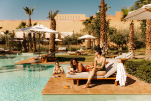 MARPH-OASIS-POOL-SUNBED-SWIMMING-THREE-WOMAN-PALMTREES-SUN-BLUE-SKY